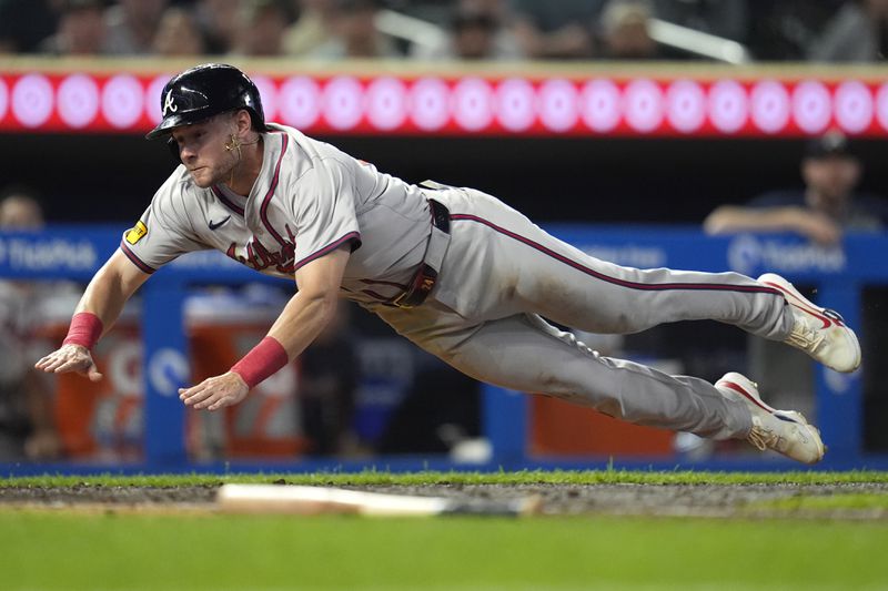 Atlanta Braves' Jarred Kelenic dives to score off a fielder's choice hit by teammate Matt Olson during the 10th inning of a baseball game against the Minnesota Twins, Tuesday, Aug. 27, 2024, in Minneapolis. (AP Photo/Abbie Parr)