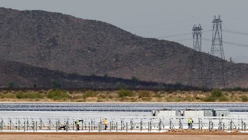 FILE - Workers continue to build rows of solar panels at a Mesquite Solar 1 facility under construction in Arlington, Ariz., Sept. 30, 2011. One of President Joe Biden's signature laws aimed to invigorate renewable energy manufacturing in the U.S. It will also helped a solar panel company reap billions of dollars. Arizona-based First Solar is one of the biggest early winners from the Democrats' Inflation Reduction Act, offering a textbook case of how the inside influence game works in Washington.(AP Photo/Ross D. Franklin, File)