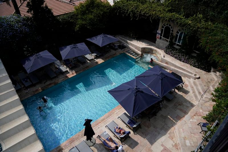 Guests swim and sunbathe at the pool at the American Colony Hotel in east Jerusalem, Sunday, Aug. 18, 2024. As Israel’s economy is suffering from the nearly 11-month war with Hamas, Jerusalem’s iconic American Colony hotel has had to lay off workers and are mulling pay cuts, said Jeremy Berkovitz, the official representative of the owners. (AP Photo/Mahmoud Illean)