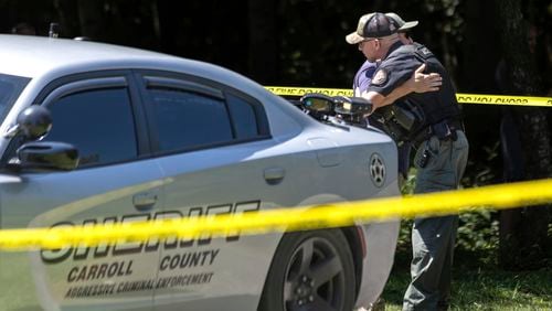 A member of the Carroll County sheriff's department, right, is hugged near the scene where authorities say a sheriff’s deputy was shot and wounded and is in “very critical” condition at a hospital, in Carrollton, Ga., Tuesday, Aug. 20, 2024. (John Spink/Atlanta Journal-Constitution via AP)