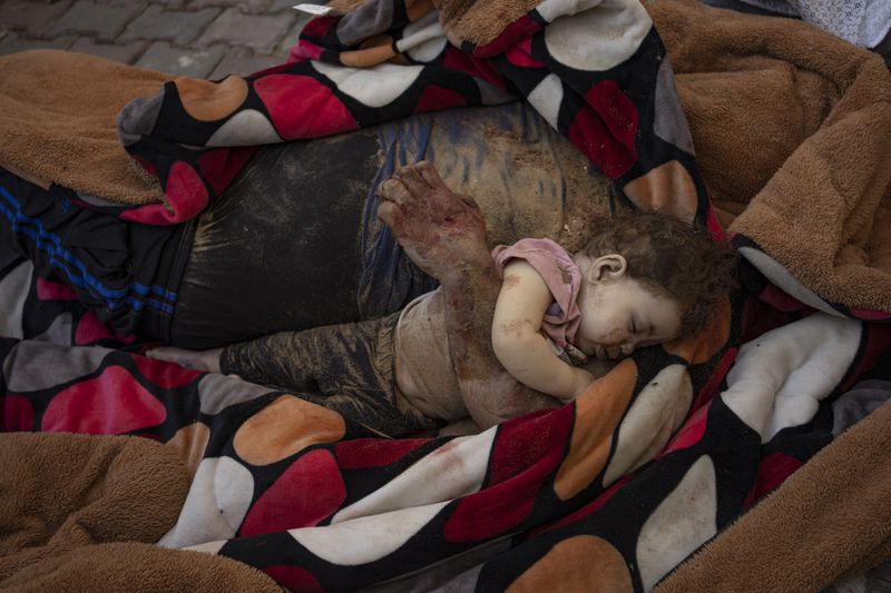 The bodies of a father and his child killed in the Israeli bombardment of the Gaza Strip, lie in front of the morgue at Al-Aqsa Hospital in Deir Al-Balah, Sunday, Oct. 22, 2023. (AP Photo/Fatima Shbair)