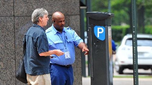Kevin Brown with PARKAtlanta helps Bruce Goldsmith figure out the parking meter pay station in this August 2012 photo. Atlanta’s City Council is expected to vote on a new parking enforcement vendor Monday to replace PARKAtlanta, whose ticketing practices raised the ire of many motorists. BRANT SANDERLIN / BSANDERLIN@AJC.COM