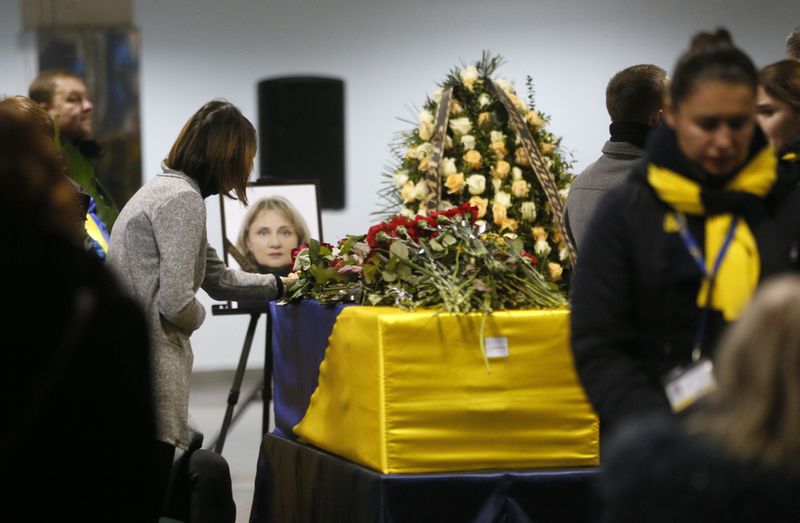 A woman lays flowers in tribute to a flight crew member of the Ukrainian plane that was shot down in January.