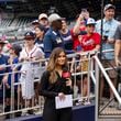 Bally reporter, Hanna Yates, broadcasts her pregame with fans standing behind her waiting for autographs before the start of a baseball game between the New York Mets and the Atlanta Braves, Monday, Sept. 30, 2024, in Atlanta. (AP Photo/Jason Allen)