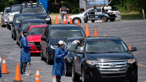 Workers at a CORE testing site at Antioch Baptist Church North in Northwest Atlanta collect covid-19 tests from a line of cars that disappears and wraps around the block Thursday afternoon July 16, 2020. Ben Gray for the Atlanta Journal-Constitution