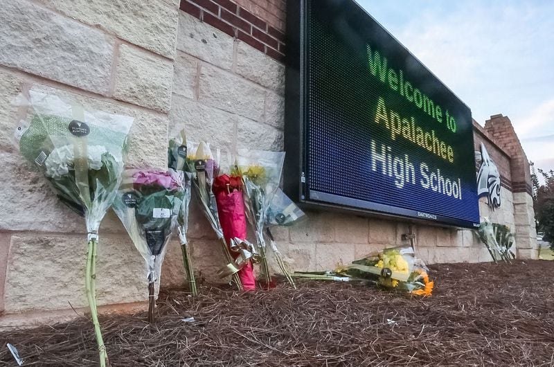 Flowers are placed at the foot of the welcome sign to Apalachee High School for a makeshift memorial on Sept. 5, 2024. (John Spink/The Atlanta Journal-Constitution/TNS)