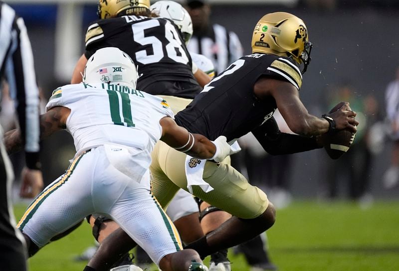 Baylor linebacker Keaton Thomas, left, pursues Colorado quarterback Shedeur Sanders, right, in the first half of an NCAA college football game Saturday, Sept. 21, 2024, in Boulder, Colo. (AP Photo/David Zalubowski)