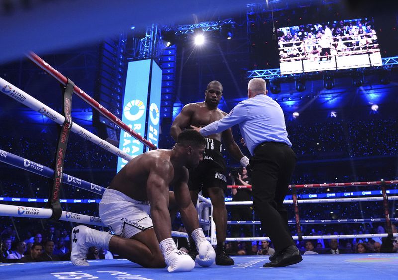 Daniel Dubois, centre, knocks down Anthony Joshua in the IBF World Heavyweight bout at Wembley Stadium, in London, Saturday, Sept. 21, 2024. (Bradley Collyer/PA via AP)