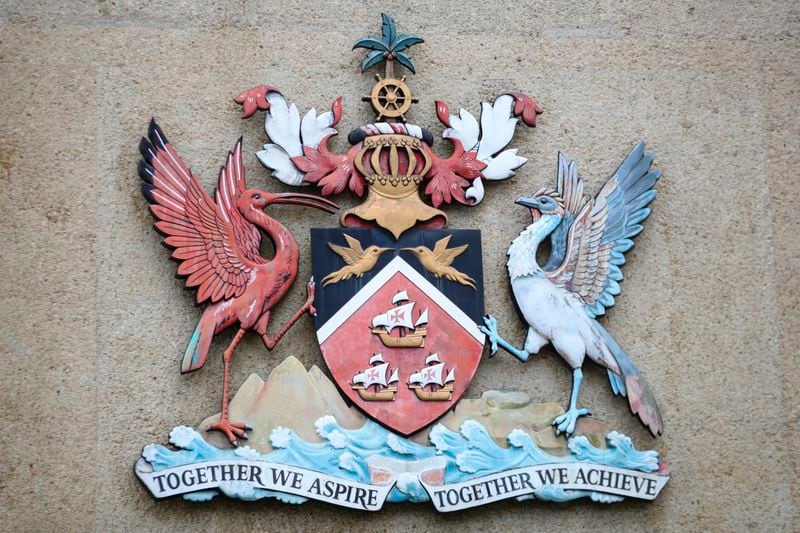 The country's coat of arms hangs at the entrance of a government building in Port-of-Spain, Trinidad and Tobago, Tuesday, Aug. 20, 2024. Prime Minister Keith Rowley announced on Sunday, Aug. 18, 2024, that the country is redrawing the island's coat of arms to remove references to European colonization, replacing Christopher Columbus' three ships with the steelpan, a popular percussion instrument. (AP Photo/Ash Allen)