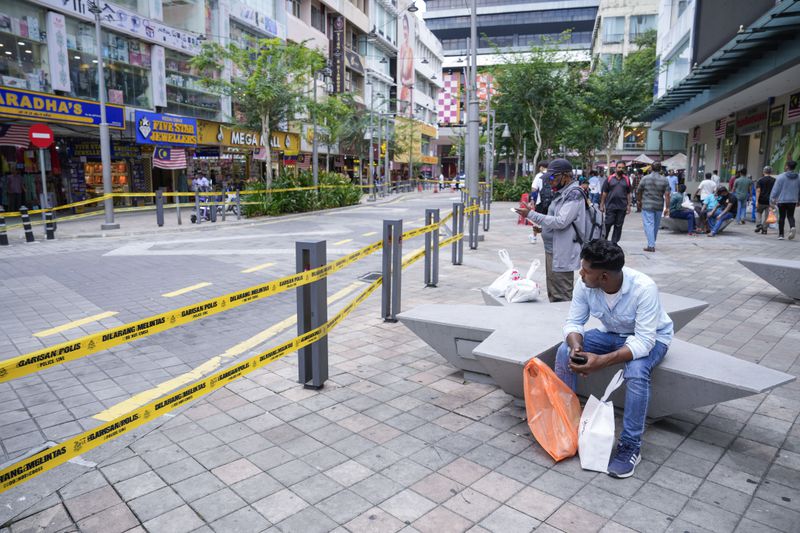 People sit next to a closed road after another deep sinkhole appeared a week after a woman fell into a sinkhole when a sidewalk caved in in Kuala Lumpur, Thursday, Aug. 29, 2024. (AP Photo/Vincent Thian)