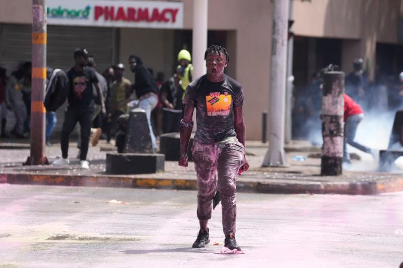 A protester gestures as Kenya police spray water canon during a protest over proposed tax hikes in a finance bill in downtown Nairobi, Kenya, Tuesday, June 25, 2024. (AP Photo/Brian Inganga)