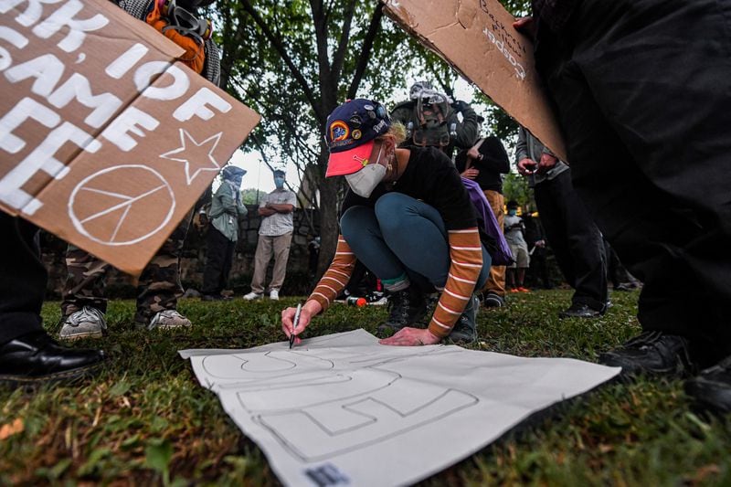 A protester writes slogan on a piece of cardboard during the Atlanta public safety training center protest during the presidential debate in Atlanta on Thursday, June 27, 2024. Both pro-Palestinian and Atlanta public safety training center protester were involved in this protest. (Ziyu Julian Zhu / AJC)
