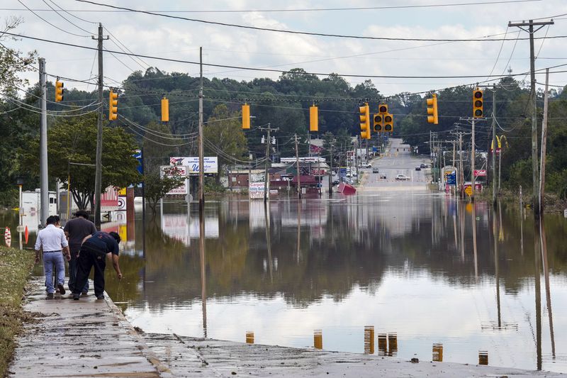 FILE - A passerby checks the water depth of a flooded road, Saturday, Sept. 28, 2024, in Morganton, N.C. (AP Photo/Kathy Kmonicek, File)