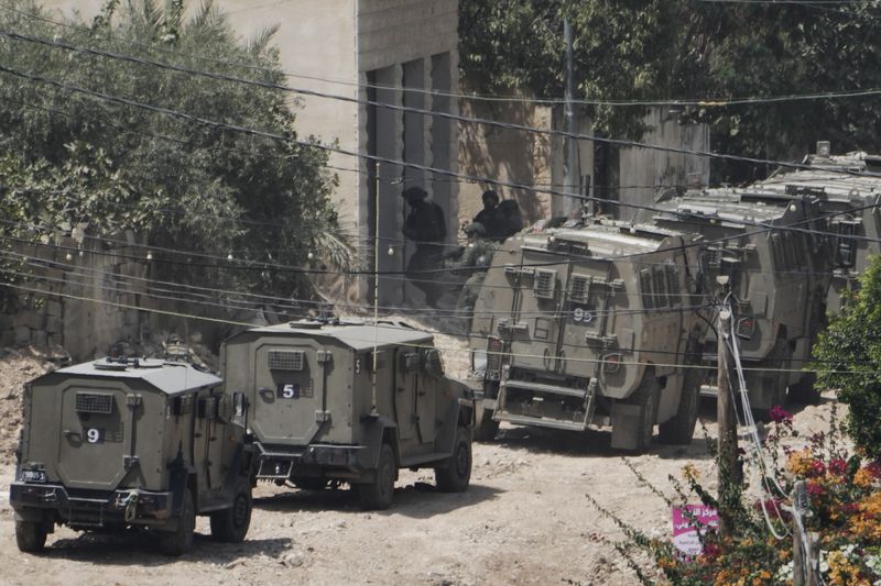 Member of the Israeli forces take position next to the armoured vehicles during a military operation in the West Bank Jenin refugee camp, Saturday, Aug. 31, 2024. (AP Photo/Majdi Mohammed)