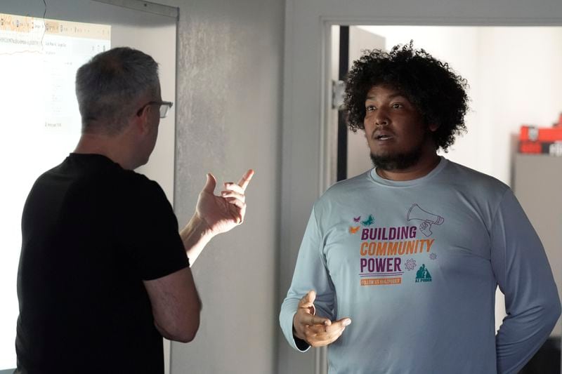 Randy Parraz, left, co-founder and president of the Organizing Institute for Democracy, helps in a role playing lecture at a Poder In Action voter canvassing event Tuesday, Sept. 3, 2024, in Phoenix. (AP Photo/Ross D. Franklin)