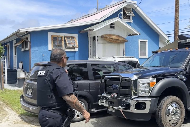 A police officer walks by the home of Ryan Routh, the man accused of an apparent attempt to assassinate Donald Trump, while FBI agents conduct a search inside, Tuesday, Sept. 17, 2024, Kaaawa, Hawaii. (AP Photo/Audrey McAvoy)