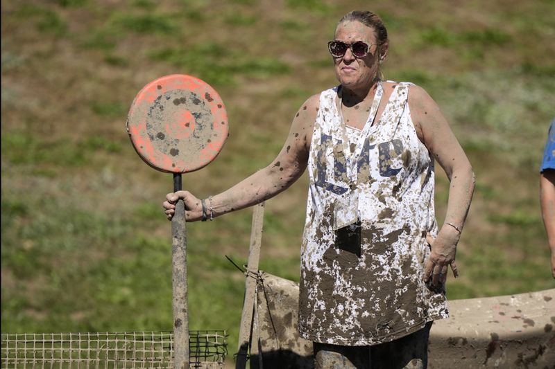 Mud-splattered sideline official Kellie Gramstorff holds a first down marker during a football game at the Mud Bowl in North Conway, N.H., Saturday, Sept. 7, 3024. (AP Photo/Robert F. Bukaty)