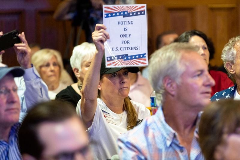 Election skeptic Maribeth Kennedy, from Hall County, holds a sign at a State Election Board meeting in Atlanta last month.