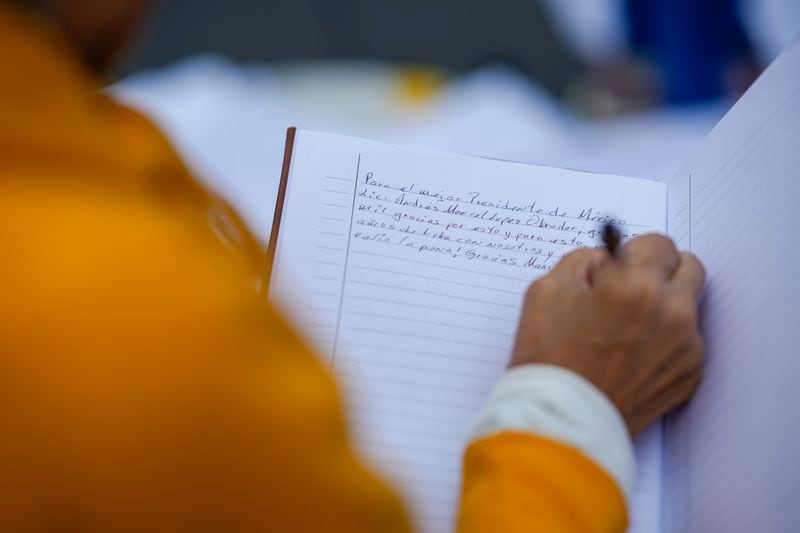 A supporter of Mexican President Andres Manuel Lopez Obrador writes him a letter as he gathers with other supporters outside the National Palace where he holds his last morning press conference, "La Mañanera," in Mexico City, Monday, Sept. 30, 2024. (AP Photo/Eduardo Verdugo)