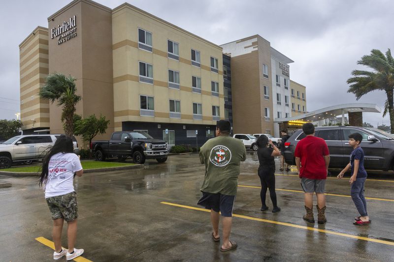 Hotels guests at the Fairfield by Marriott Inn & Suites step out to look at some of the damage, top center, to the hotel as the eye of Hurricane Francine moves over the area causing a short respite in the rain, Wednesday, Sept. 11, 2024, in in Houma, La. (Chris Grange/The Times-Picayune/The New Orleans Advocate via AP)