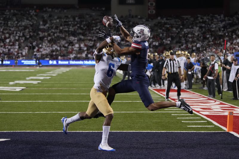 FILE - Arizona wide receiver Tetairoa McMillan (4), right, catches a touchdown pass in front of UCLA defensive back John Humphrey during the second half of an NCAA college football game Saturday, Nov. 4, 2023, in Tucson, Ariz. (AP Photo/Rick Scuteri, File)