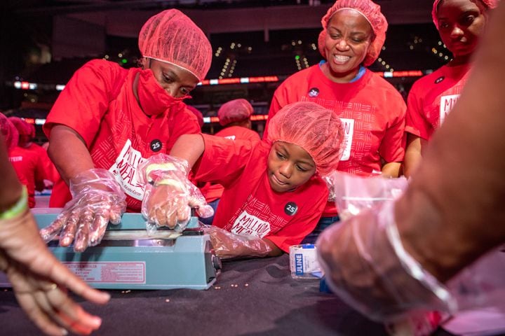 Candi Glaze (left), 7-year-old Tyrone Glaze and Jennice Gist pack red lentil jambalaya kits.  (Jenni Girtman for The Atlanta Journal-Constitution)