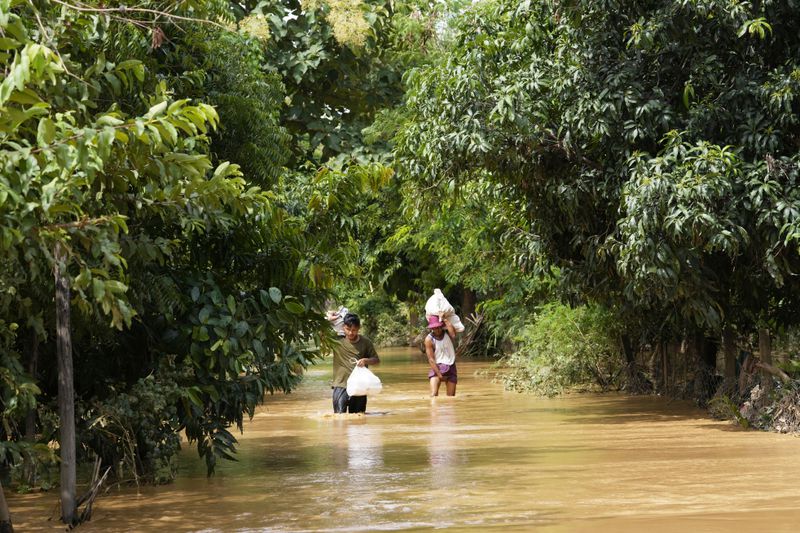 Local residents carrying food wade through a flooded road in Naypyitaw, Myanmar, Saturday, Sept. 14, 2024. (AP Photo/Aung Shine Oo)