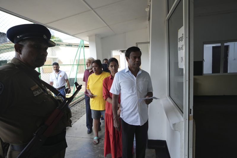 Sri Lankan police officer stands guard as voters queue to cast their vote at a polling center for presidential election in Colombo, Sri Lanka, Saturday, Sept. 21, 2024. (AP Photo/Rajesh Kumar Singh)