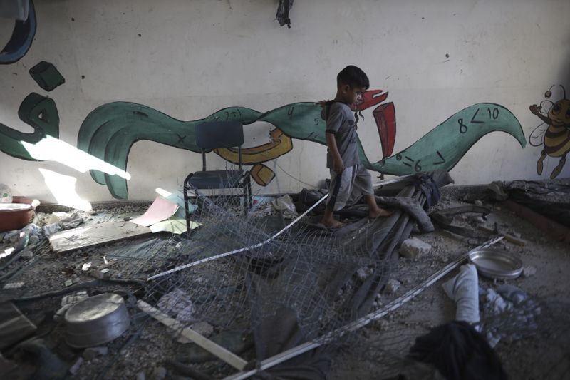 A Palestinian child navigates through heavy damage to a UNRWA school sheltering displaced persons the day after a nearby house was targeted by Israeli bombardment in Khan Younis, southern Gaza Strip, Friday, June 21, 2024. (AP Photo /Jehad Alshrafi)