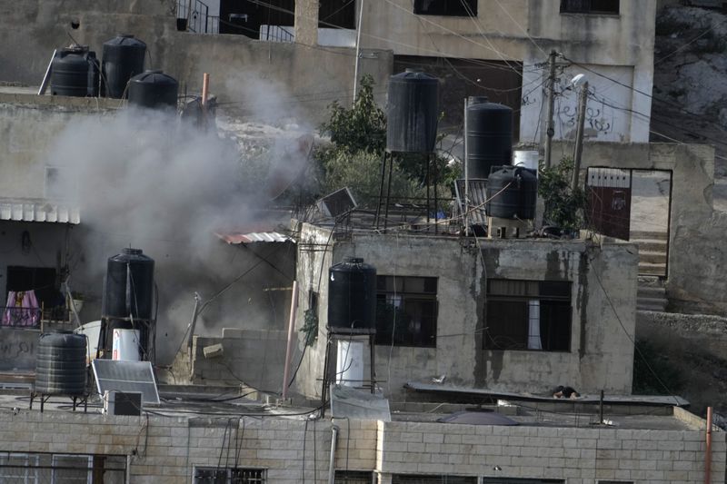 EDS NOTE: GRAPHIC CONTENT - An explosion is seen with three bodies lie motionless on rooftops in the West Bank town of in the West Bank town of Qatabiya during a raid, Thursday, Sept. 19, 2024. (AP Photo/Majdi Mohammed)