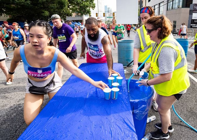 Atlanta Track Club volunteers fill cups of water for runners to take during the 55th running of The Atlanta Journal-Constitution Peachtree Road Race at "Cardiac Hill" on Peachtree Road NW in Atlanta on Thursday, July 4, 2024. (Seeger Gray / AJC)