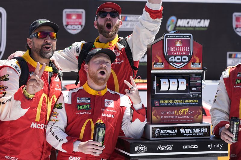 Tyler Reddick and crew stand by the winner's trophy after a NASCAR Cup Series auto race at Michigan International Speedway, Monday, Aug. 19, 2024, in Brooklyn, Mich. (AP Photo/Carlos Osorio)