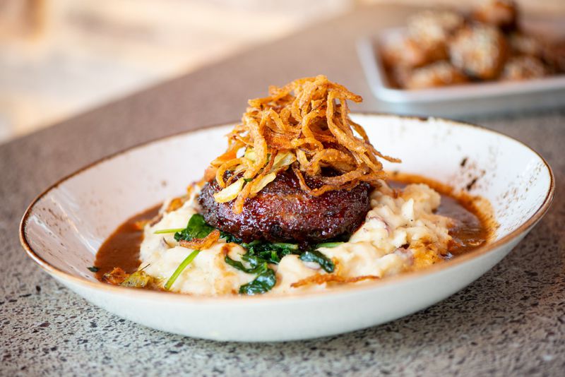 BBQ Bison Meatloaf with all-natural Wyoming bison, smoked bacon, red skin potato mash, sauteed spinach, and haystack onions. Photo credit- Mia Yakel.