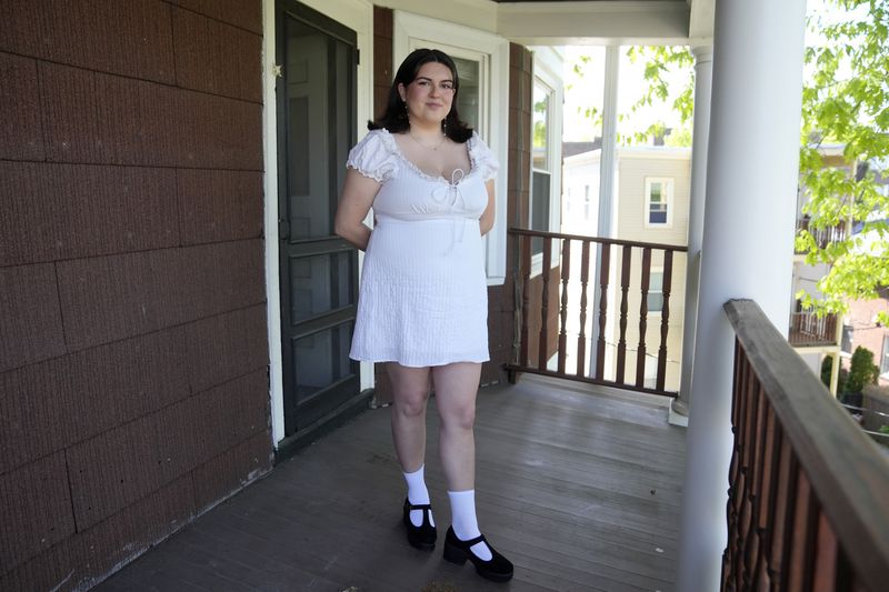 Daniella López White, of Hawaii, poses for a photo on Tuesday, May 14, 2024, on the porch of her apartment, in Boston. López White, who graduated from Emerson College in Boston this month and is on a tight budget, said TikTok influencers have helped her with tips on how to find affordable clothes at places like H&M and thrift shops. (AP Photo/Steven Senne)