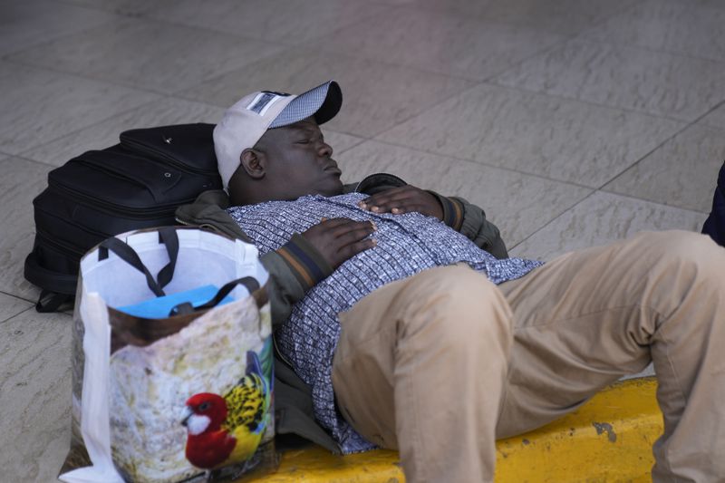 A stranded passenger takes a nap as he wait for delayed flight out of JKIA airport in Nairobi, Kenya Wednesday, Sep. 11, 2024. Hundreds of workers at Kenya's main international airport demonstrated on Wednesday against a planned deal between the government and a foreign investor. Planes have remained grounded, with hundreds of passengers stranded at the airport. (AP Photo/Brian Inganga)