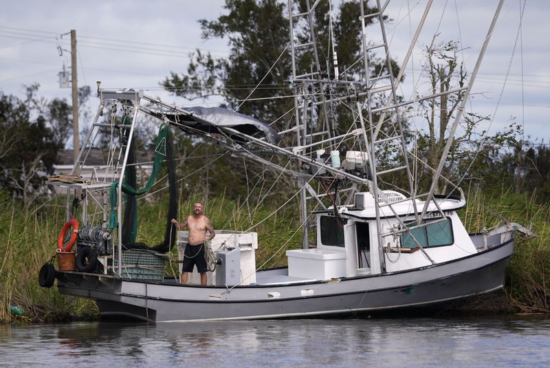 Chad Luke calls out to family for help in getting his shrimp boat from being grounded on the bank in the aftermath of Hurricane Francine, Thursday, Sept. 12, 2024, in Dulac, La. (AP Photo/Gerald Herbert)