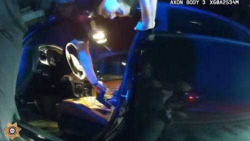 A Forsyth County sheriff's deputy recovers a handgun from the front seat of a Dodge Charger SRT Hellcat. The sheriff's office said the driver led multiple deputies on a chase that hit 145 mph on Ga. 400.