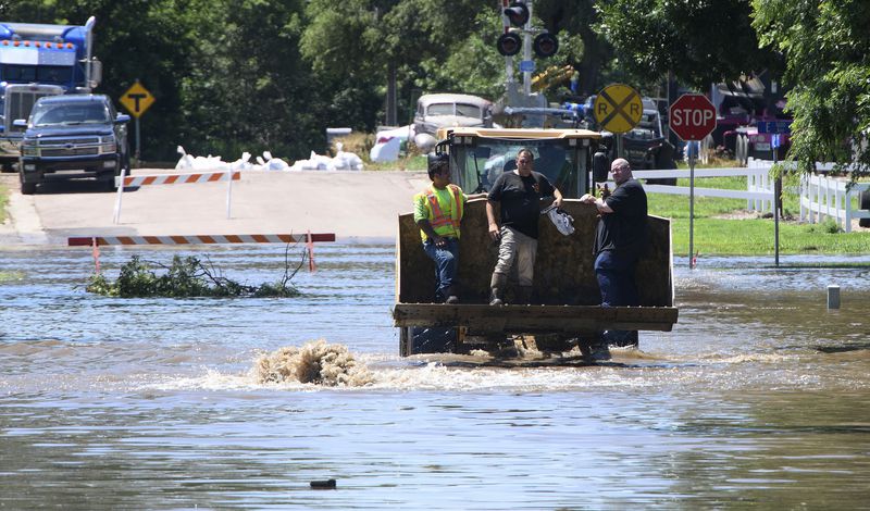 A person holds a dog while being evacuated in the bucket of a front end loader in Hawarden, Iowa, Saturday, June 22, 2024, in the wake of flooding from the Big Sioux River. Massive upstream rainfall sent the river over its banks in Hawarden causing massing flooding that prompted evacuations. (Tim Hynds/Sioux City Journal via AP)