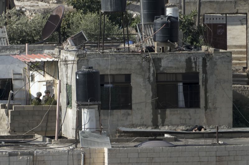 EDS NOTE: GRAPHIC CONTENT - Israeli soldiers stand near three bodies on rooftops in the West Bank town of Qatabiya during a raid, Thursday, Sept. 19, 2024. (AP Photo/Majdi Mohammed)