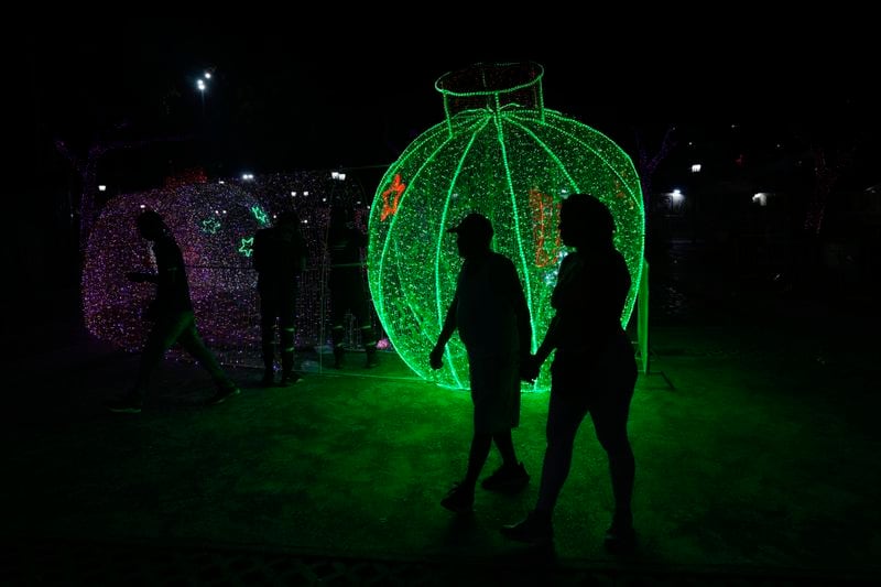 People walk past Christmas decorations in Caracas, Venezuela, Tuesday, Oct. 1, 2024. (AP Photo/Ariana Cubillos)