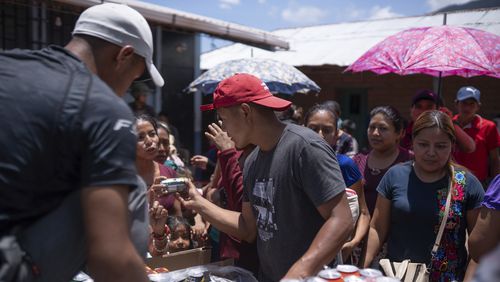 Locals in Guatemala offer sodas to Mexicans who fled their town of Amatenango, Mexico and crossed the border to Ampliación Nueva Reforma, Guatemala, to escape cartel violence in Mexico, Thursday, July 25, 2024. Some of the refugees are staying at the school and others at local's homes. (AP Photo/Santiago Billy)