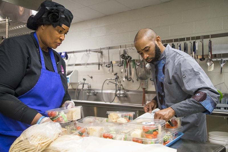 Chef Reggie Sloan (right), district chef for Fulton County Schools, and kitchen food service worker Valerie Gardner (left) prepare meals in the cafeteria kitchen at Heards Ferry Elementary School in Sandy Springs on Monday, Feb. 3, 2020. A new Georgia law increases pensions for food service workers and other school employees. (AJC file photo)