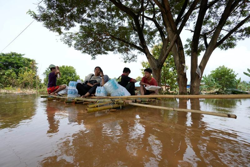 Flood victims rest on a bamboo raft with their food on a flooded road in Naypyitaw, Myanmar, Saturday, Sept. 14, 2024. (AP Photo/Aung Shine Oo)