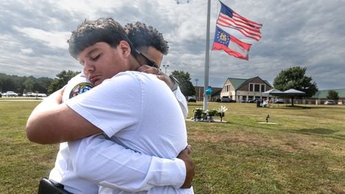 Ninth-grade student Jose Ortiz, left, is hugged by Georgia State Chaplain Ronald Clark as students and well-wishers arrived Thursday with flowers to place at the flagpole at Apalachee High School in Winder. A 14-year-old is accused of shooting and killing two fellow students and two teachers and injuring nine others Wednesday at Apalachee. (John Spink/AJC)