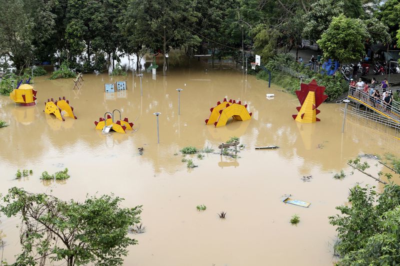 People look on a submerged dragon structure in a playground, following Typhoon Yagi in Hanoi, Vietnam on Tuesday, Sept. 10, 2024. (AP Photo/Huy Han)