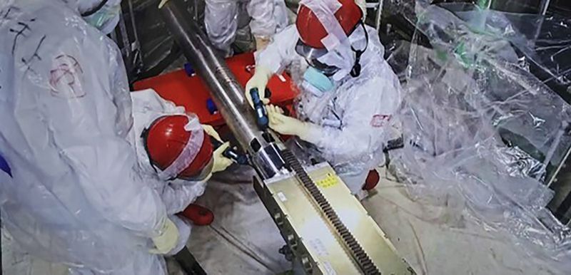 In this photo released by Tokyo Electric Power Company Holdings (TEPCO), monitoring workers rearrange the push-in pipes, at the Fukushima Daiichi nuclear power plant in Okuma, Fukushima prefecture, northern Japan Tuesday, Sept. 10, 2024. An extendable robot began on Tuesday a two-week mission to retrieve the first sample of melted fuel debris from inside one of three damaged reactors at the nuclear power plant.(Tokyo Electric Power Company Holdings via AP)