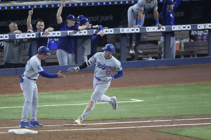 Los Angeles Dodgers first base coach Clayton McCullough, left, congratulates Shohei Ohtani (17) after Ohtani hit a home run scoring Andy Pages, during the sixth inning of a baseball game against the Miami Marlins, Thursday, Sept. 19, 2024, in Miami. (AP Photo/Wilfredo Lee)