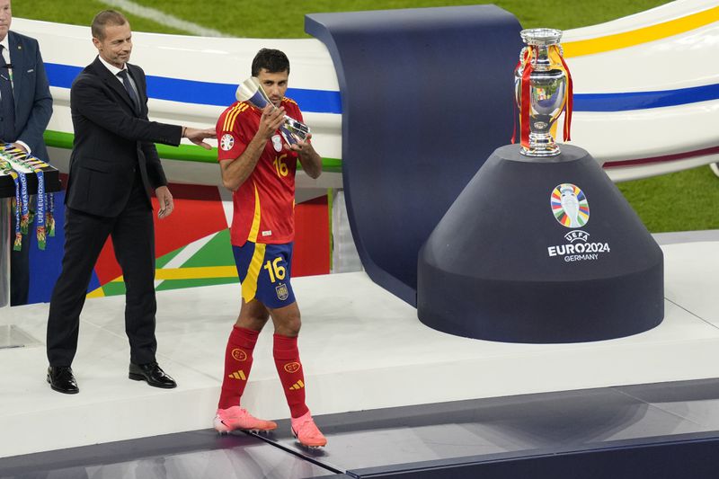 FILE - Spain's Rodri holds the player of the tournament trophy after the final match between Spain and England at the Euro 2024 soccer tournament in Berlin, Germany, July 14, 2024. Jude Bellingham and Rodri have key starring roles for title-winning soccer clubs and their national teams. Neither is currently playing matches. (AP Photo/Andreea Alexandru, File)