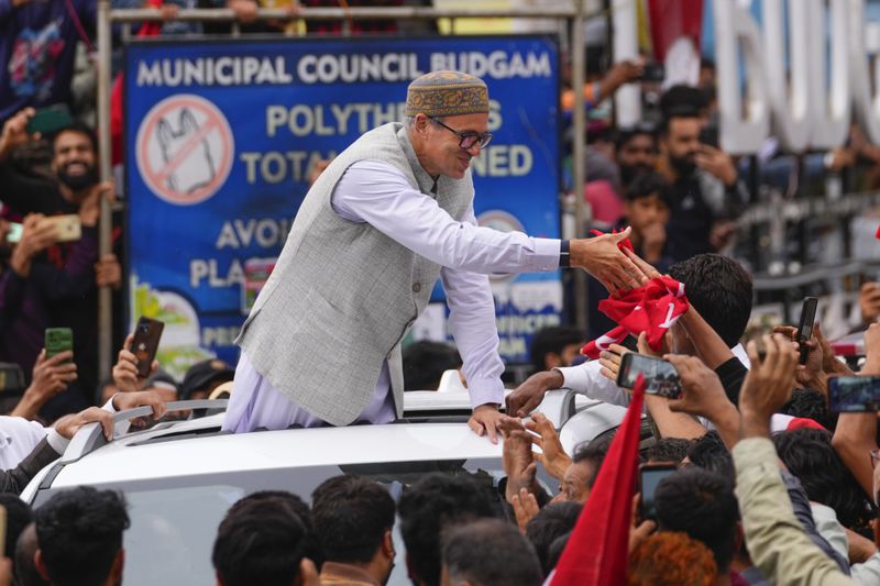 Jammu and Kashmir National Conference (JKNC) party leader Omar Abdullah, standing on car shakes hands with supporters as he celebrates his victory in the election for a local government in Indian controlled Kashmir, Budgam, Tuesday, Oct. 8, 2024. (AP Photo/Dar Yasin)