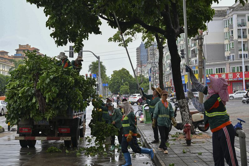 In this image released by Xinhua News Agency, workers cut redundant branches off of trees along a street ahead of the landfall of typhoon Yagi in Haikou, south China's Hainan Province, Thursday, Sept. 5, 2024. (Guo Cheng/Xinhua via AP)